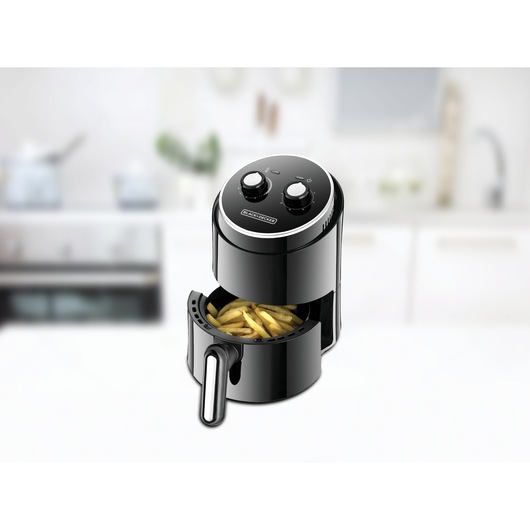 BLACK+DECKER air fryer AF100 with open drawer containing fries, shown in a modern kitchen.