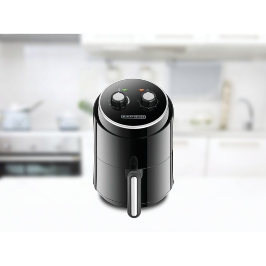 BLACK+DECKER AF100 black air fryer with two control dials, shown on a kitchen counter.
