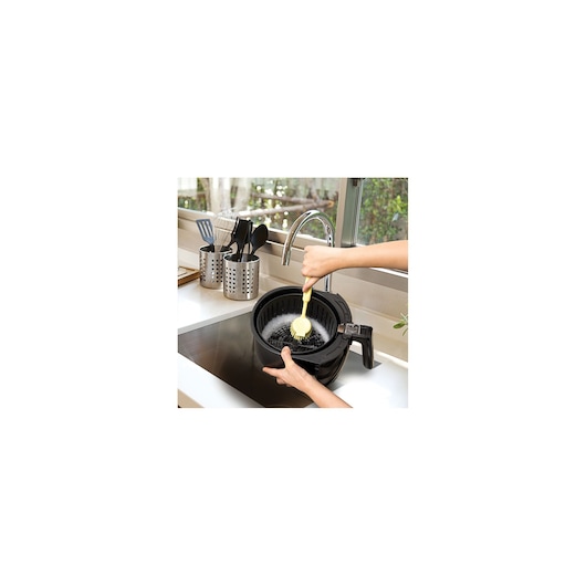 BLACKDECKER AF250G air fryer basket being cleaned under a faucet in a kitchen sink.