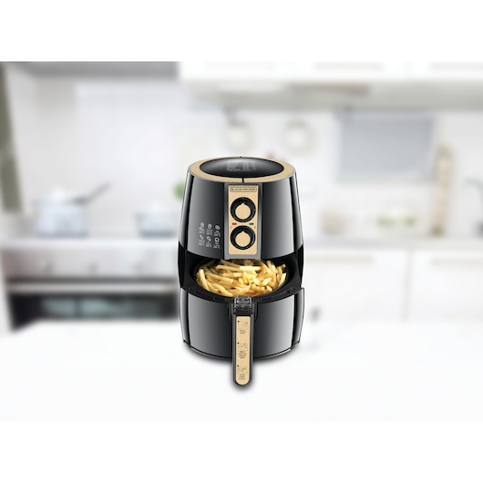 BLACKDECKER AF300 air fryer with fries in basket, black and gold, front angle, on kitchen counter.