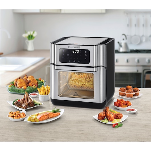 BLACKDECKER AOF100 digital air fryer oven with fries inside, surrounded by assorted cooked dishes, front angle.