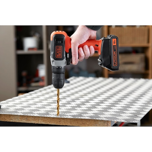 BLACK+DECKER BCD001C2K cordless drill in use drilling into a metal sheet, close-up side view.