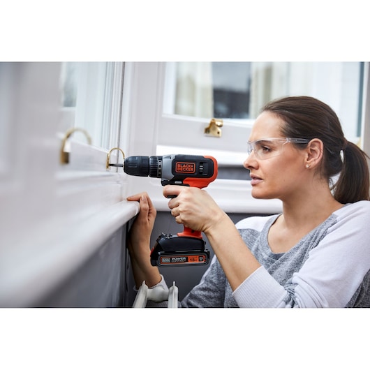 BLACK+DECKER cordless drill BCD001C2K used for DIY near a window.