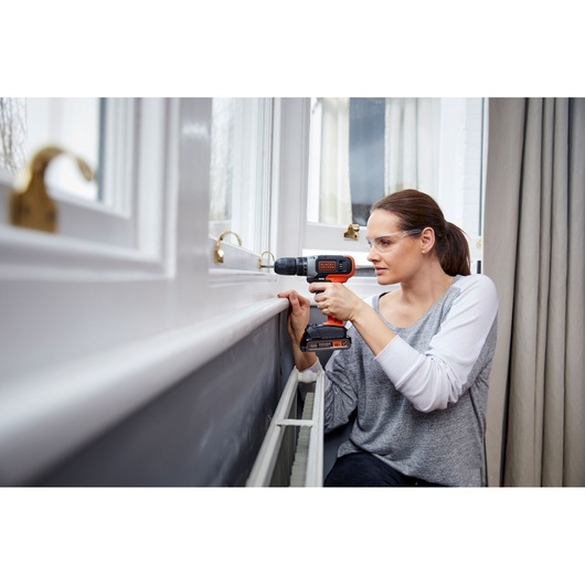 BLACKDECKER BCD001C2K cordless drill used indoors near a window.