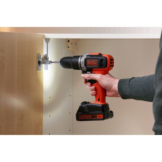 Photo of BLACK+DECKER BCD003C2K cordless drill used to install a hinge inside a cabinet.