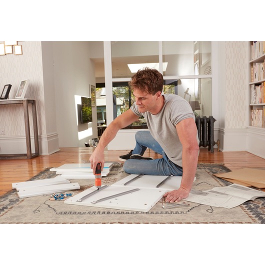 BLACKDECKER BCF603C cordless screwdriver used for assembling furniture panels indoors.