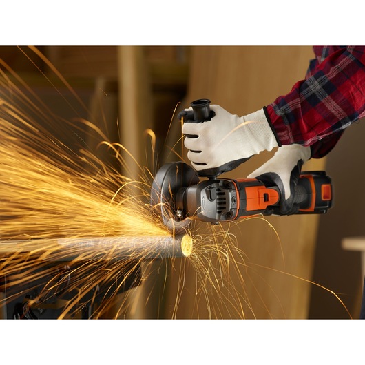 BLACKDECKER BCG720N cordless angle grinder cutting metal pipe, sparks flying, close-up view.