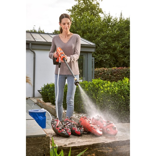 BLACKDECKER BCPC18B cordless pressure washer cleaning dirty red cleats outdoors.