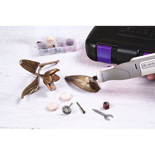 BLACK+DECKER BCRT8IPETK rotary tool polishing metal flower with accessory bits and carrying case.