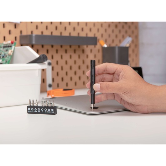 BLACKDECKER BD40K27 precision screwdriver held above a laptop in a workshop setting.