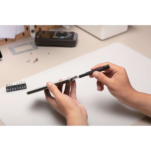 BLACKDECKER BD40K27 precision screwdriver set used to open a smartphone, photography at desktop angle.
