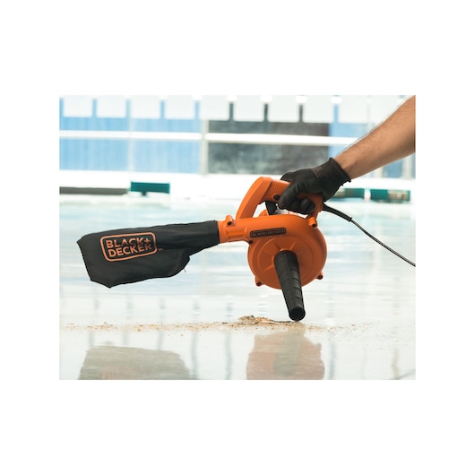 BLACKDECKER BDB530 orange handheld blower with dust bag cleaning a smooth indoor surface.
