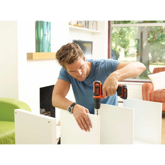 BLACKDECKER BDCDD12 cordless drill used for furniture assembly indoors.