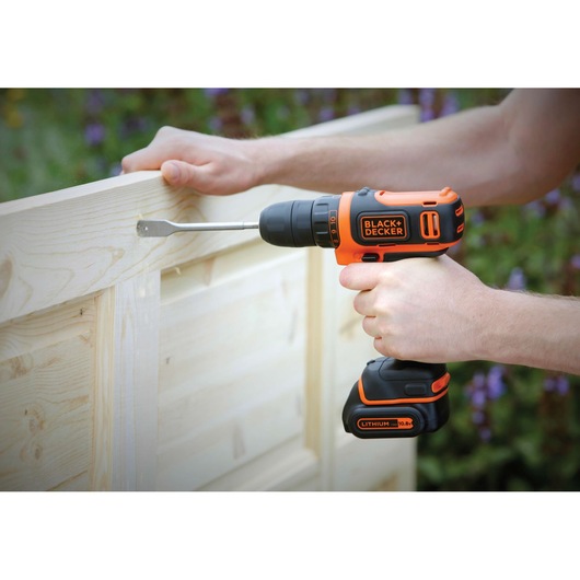 Photo of BLACK+DECKER BDCDD12 cordless drill in use on a light wood gate.