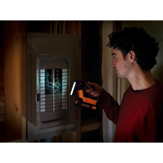 Photo of BLACKDECKER BDCF18 LED work light illuminating an electrical panel, held by a person in a red shirt.