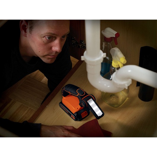 Photo of BLACKDECKER BDCF18 flashlight under sink, with spray bottles and cleaning cloth nearby.