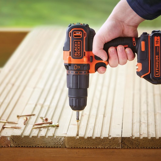 BLACKDECKER BDCHD18KB cordless drill being used to drive a screw into wooden planks, close-up angle.