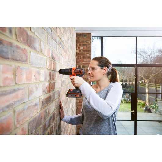 BLACKDECKER BDCHD18KB cordless hammer drill used on brick wall indoors.