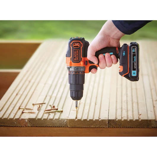 BLACKDECKER BDCHD18KST cordless drill held over wooden planks with screws, side angle.