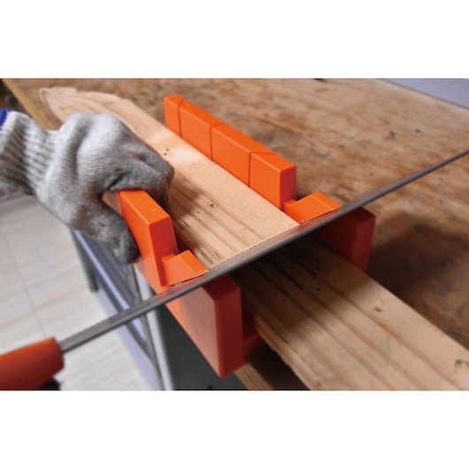 BLACKDECKER BDHT20346 orange miter box holding wood while being cut with a hand saw, close-up view.