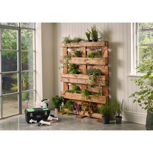 BLACKDECKER BDST60120 tool box and garden tools next to a wood pallet vertical herb garden indoors, side angle.