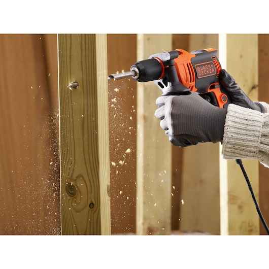 BLACKDECKER BEH550 corded drill in use on wood, close-up of drill creating sawdust, photography.