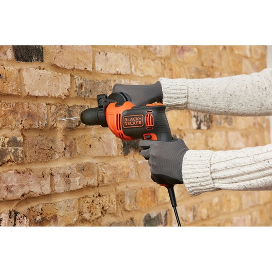 BLACK+DECKER BEH710K corded drill in use on brick wall, orange and black design, photography category.