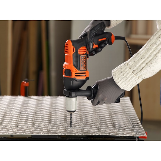 BLACKDECKER BEH850K corded hammer drill used on metal sheet by gloved hands, close-up.
