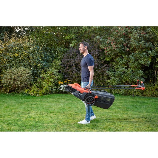 BLACKDECKER BEMW471BH lawn mower being carried by a person in a garden