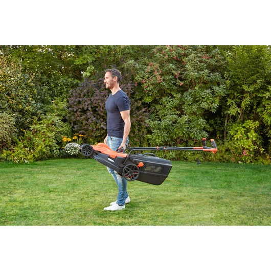 BLACKDECKER BEMW481BH lawn mower with handle being carried by person outdoors on grass.