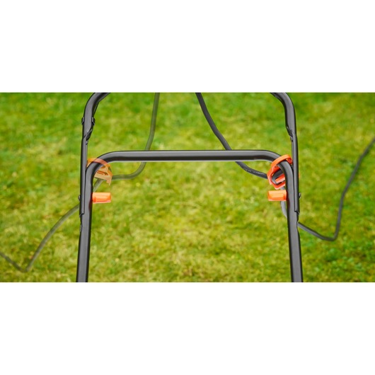 BLACKDECKER BEMW481BH lawn mower handle close-up with orange clips and cord against grass background.