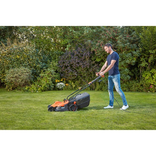 Photo of BLACKDECKER BEMW481ES electric lawn mower on grass, corded, being used outdoors.