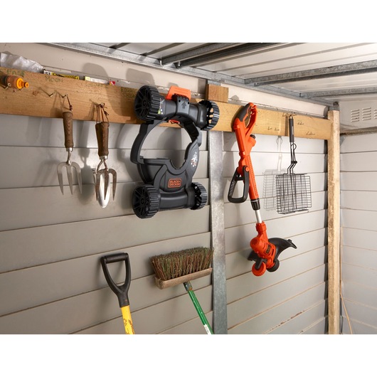 Photo of BLACKDECKER BESTA530CM lawn mower and trimmer hung on shed wall with garden tools.