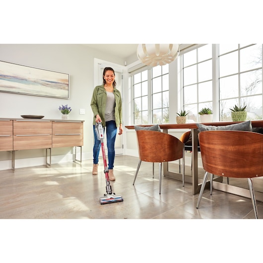 BLACKDECKER BHFE620J cordless stick vacuum used to clean a tiled dining room floor near wood chairs and table.