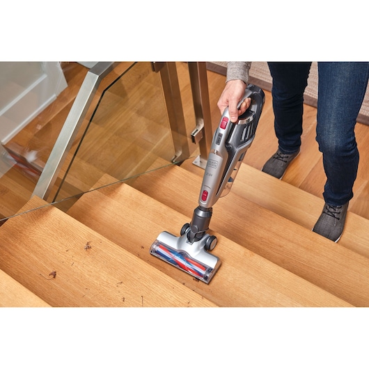 BLACKDECKER BHFE620J cordless vacuum cleaner used on wooden stairs, photography showing cleaning action.
