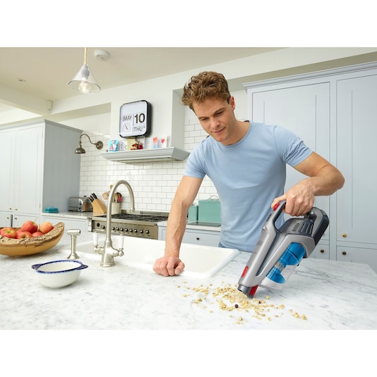 BLACKDECKER BHFE620J cordless handheld vacuum cleaner used on kitchen counter to clean dry food crumbs.