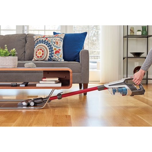 BLACKDECKER BHFE620J stick vacuum cleaning hardwood floor under low table in living room side view