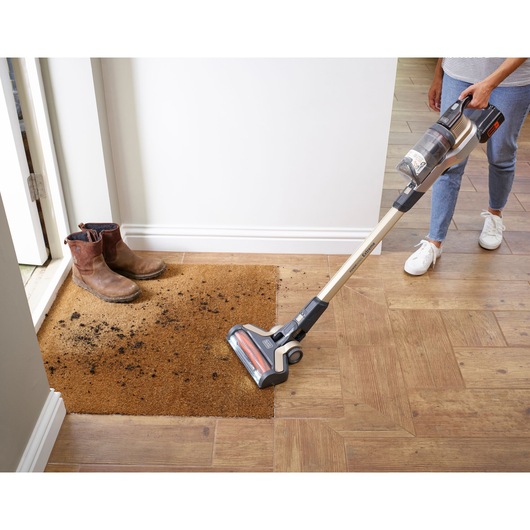 BLACKDECKER BHFEV36B2D cordless stick vacuum cleaning a dirty doormat, floor view, product in use.
