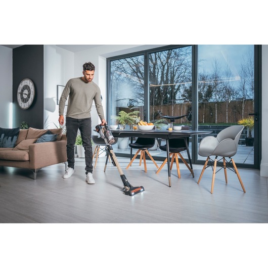 Photo of BLACKDECKER BHFEV36B2D cordless stick vacuum in use on a light wood floor in a modern living room.