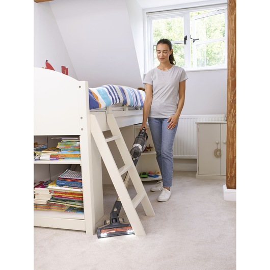 Photo of BLACKDECKER BHFEV36B2D cordless vacuum cleaning beige carpet near bunk bed and bookshelf in bedroom.