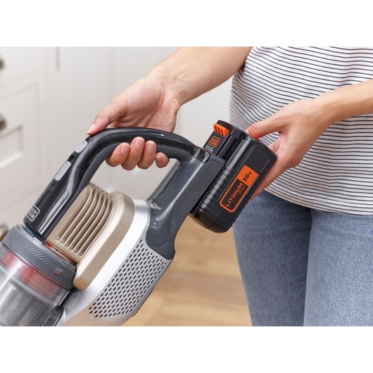 Photo of BLACKDECKER cordless vacuum BHFEV36B2D with lithium 36V battery being inserted by hand.