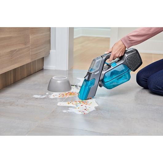 BLACKDECKER BHSB315J handheld wet dry vacuum cleaning spilled cereal and milk on kitchen floor, side angle