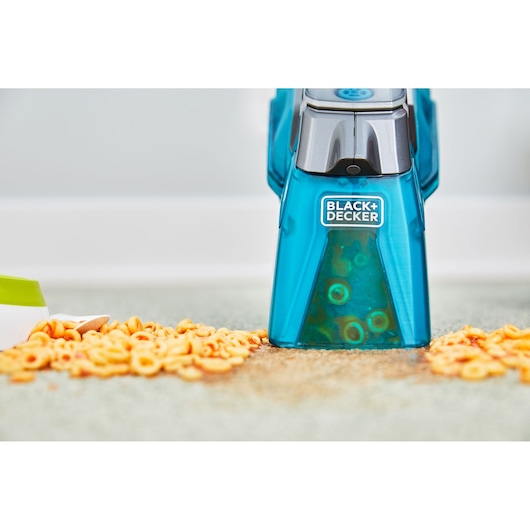 BLACK+DECKER BHSB315J carpet cleaner removing spilled pasta from carpet, close-up front angle.
