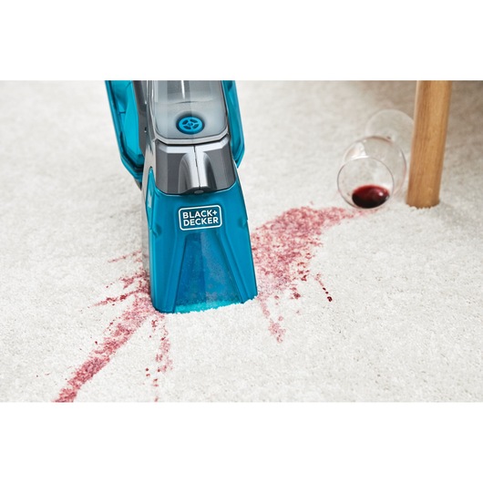 BLACKDECKER BHSB315J carpet cleaner removing red wine stain from white carpet, angled front view.