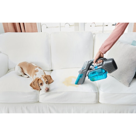 BLACKDECKER BHSB315J handheld vacuum cleaning pet stain on white sofa, front angle.