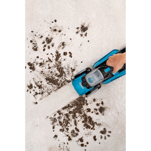 BLACKDECKER BHSB320JP upright carpet cleaner in use, cleaning dirt from beige carpet, top view.