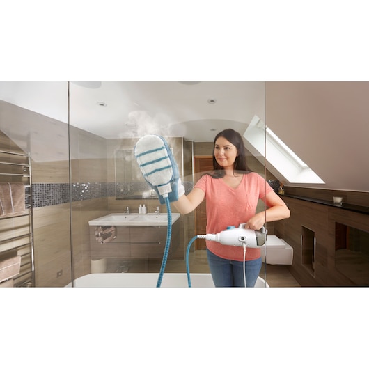 Photo of BLACKDECKER BHSM166DSM steam cleaner with hand mitt attachment cleaning a glass shower door in a bathroom.