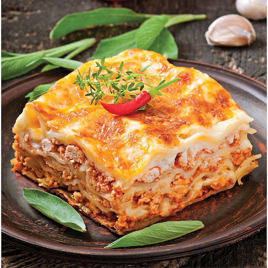 Photo of BLACKDECKER BX390, close-up of a slice of lasagna on a brown plate, garnished with herbs and chili pepper.