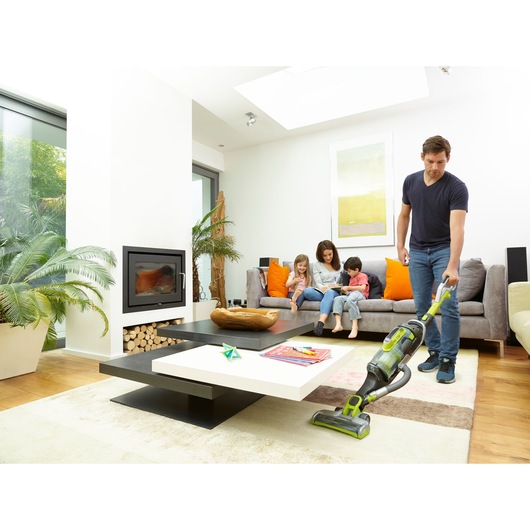 BLACKDECKER CUA525BHA vacuum cleaner being used in a modern living room near a sofa and coffee table.