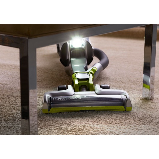 BLACKDECKER CUA525BHA vacuum cleaner with LED light cleaning under furniture on carpet, close-up front view